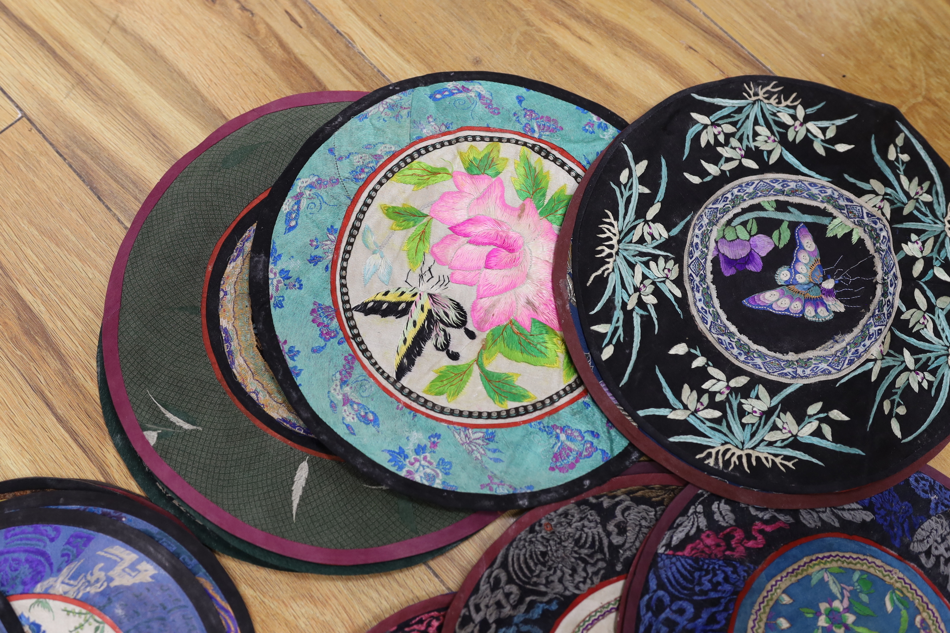 Forty two Chinese embroidered circular mats with damask borders, largest 25cm in diameter